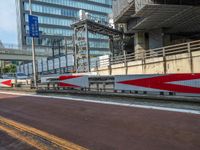 the red and silver train is on the street and on its side of the road