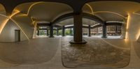 a fish eye view of an empty public building with pillars and arches in the background