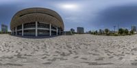 a spherical image of an empty arena in the middle of city, looking down at a man walking