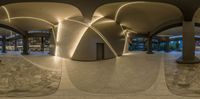 a fisheye photo of inside an indoor building with round arches and stone flooring