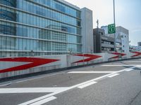 red and white barriers on road with buildings in background near sidewalk with cars and pedestrian crossing sign