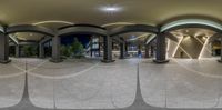 a circular photo taken on the outside side of a building with arches, pillars, and stone floors