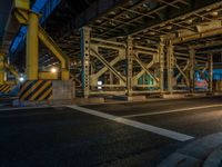 the car is parked underneath an overpass at night time, while no other cars are present