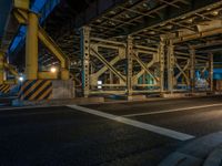 the car is parked underneath an overpass at night time, while no other cars are present