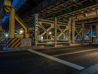 the car is parked underneath an overpass at night time, while no other cars are present