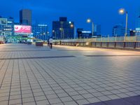 people standing on a subway platform with many buildings in the background at night light in tokyo