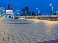 people standing on a subway platform with many buildings in the background at night light in tokyo