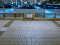 people standing on a subway platform with many buildings in the background at night light in tokyo