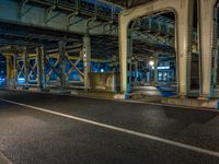 the car is parked underneath an overpass at night time, while no other cars are present