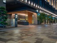 a large brick sidewalk with a store front at night time and a sign that says