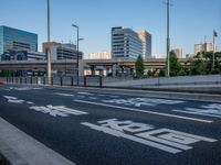 an empty road with a street sign at the curb in front of an office building