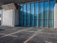 a sidewalk that has several glass doors next to it with buildings in the background behind