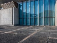 a sidewalk that has several glass doors next to it with buildings in the background behind