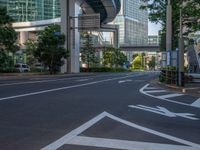 an empty road with a street sign at the curb in front of an office building