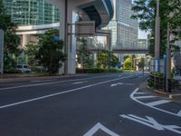 an empty road with a street sign at the curb in front of an office building