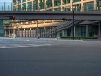 an empty road with a street sign at the curb in front of an office building