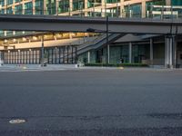 an empty road with a street sign at the curb in front of an office building