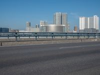 the highway and bridge leading to a city in japan and has tall buildings and blue skies