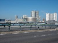 the highway and bridge leading to a city in japan and has tall buildings and blue skies