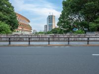 a view of a stadium from the street, showing many trees and bushes in the distance