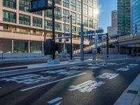 an empty road with a street sign at the curb in front of an office building