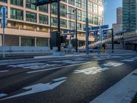 an empty road with a street sign at the curb in front of an office building