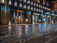 a large brick sidewalk with a store front at night time and a sign that says