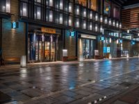 a large brick sidewalk with a store front at night time and a sign that says