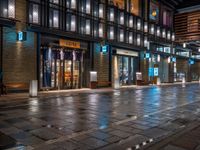 a large brick sidewalk with a store front at night time and a sign that says