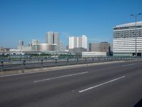 the highway and bridge leading to a city in japan and has tall buildings and blue skies