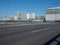 the highway and bridge leading to a city in japan and has tall buildings and blue skies