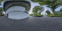 an empty car park sits next to a concrete building that has a circular roof on it