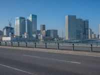 the highway and bridge leading to a city in japan and has tall buildings and blue skies