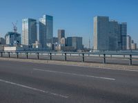 the highway and bridge leading to a city in japan and has tall buildings and blue skies