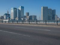 the highway and bridge leading to a city in japan and has tall buildings and blue skies