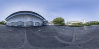 a 360 - view image shows a circular building in front of a blue sky and trees