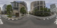 two wide angle roads with traffic and several buildings in the background of the image