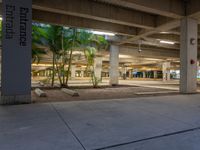 an empty parking garage at night with trees and palm trees in the foreground and a light that reads entrance