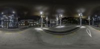 the view from an airport at night, shows an empty roadway surrounded by lit buildings