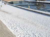 the man is walking along a frozen river bank with an empty bench and a fire hydrant