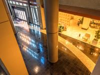 a large hallway with light reflecting from some windows at night time, has various planters on the counter