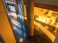 a large hallway with light reflecting from some windows at night time, has various planters on the counter