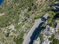 a car driving along the top of a steep mountain next to the ocean with a shadow of a car on it