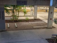 there is an empty parking garage under a building that features columns and steps, but with a bicycle leaning on a wall