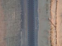 a long highway that has a lone car on it in the middle of nowhere in the desert