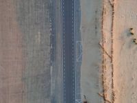 a long highway that has a lone car on it in the middle of nowhere in the desert