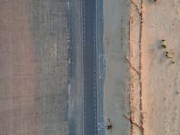 a long highway that has a lone car on it in the middle of nowhere in the desert