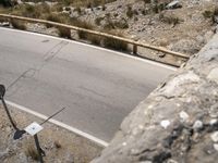 a person riding a skateboard on a long road by rocks and a cliff next to a road