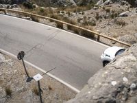 a person riding a skateboard on a long road by rocks and a cliff next to a road