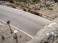 a person riding a skateboard on a long road by rocks and a cliff next to a road